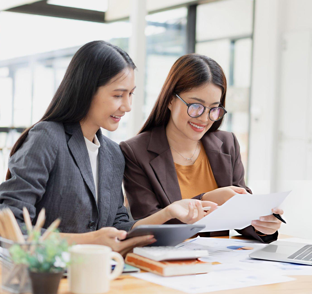 two women at work smiling looking at a paper