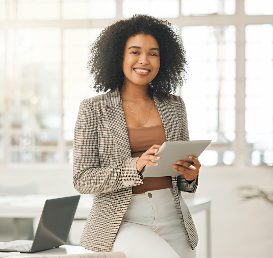 woman smiling in a suit holding a tablet