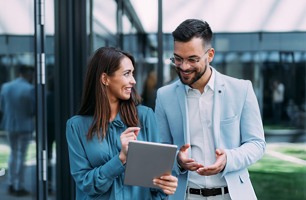 woman and man smiling while looking at a tablet